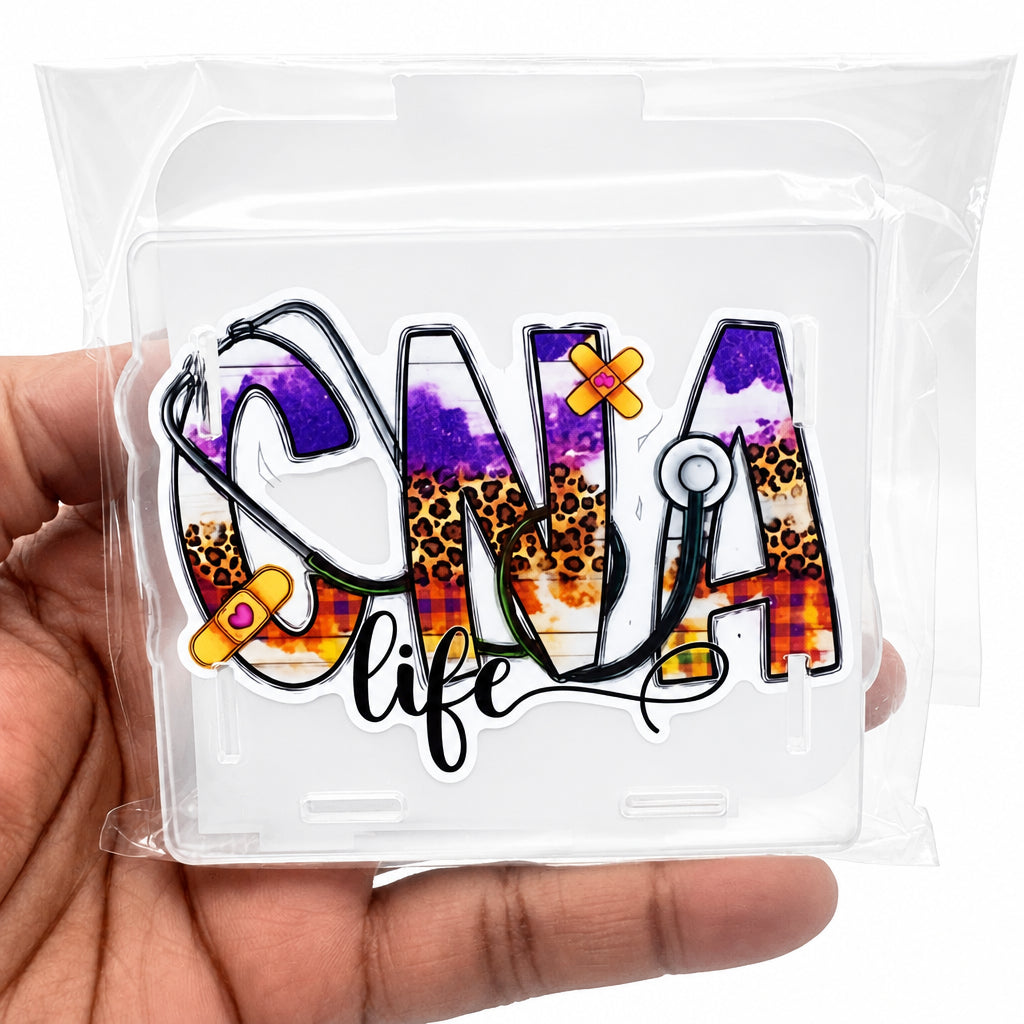 A hand holding a clear plastic case containing a die-cut sticker that reads 'CNA life' with a purple, leopard-print, and orange medical-themed design.