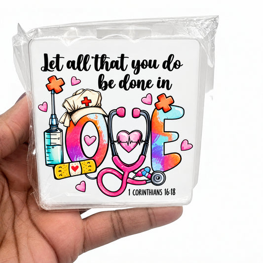 A hand holding a clear plastic case featuring a colorful medical-themed design with the phrase 'Let all that you do be done in love' and illustrations of a stethoscope, syringe, nurse hat, and hearts.