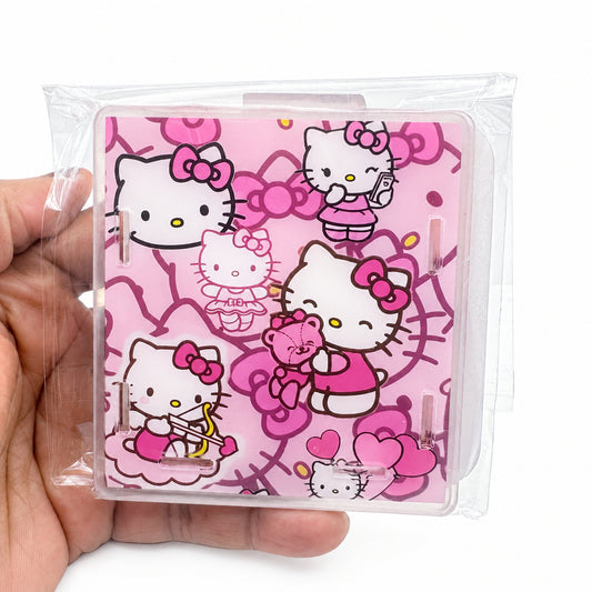 A hand holding a clear plastic-wrapped square item featuring a pink Hello Kitty cartoon pattern with multiple Hello Kitty illustrations and bows.
