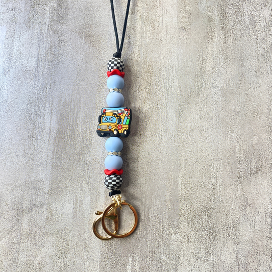 Beaded keychain with a colorful bus charm on a textured surface