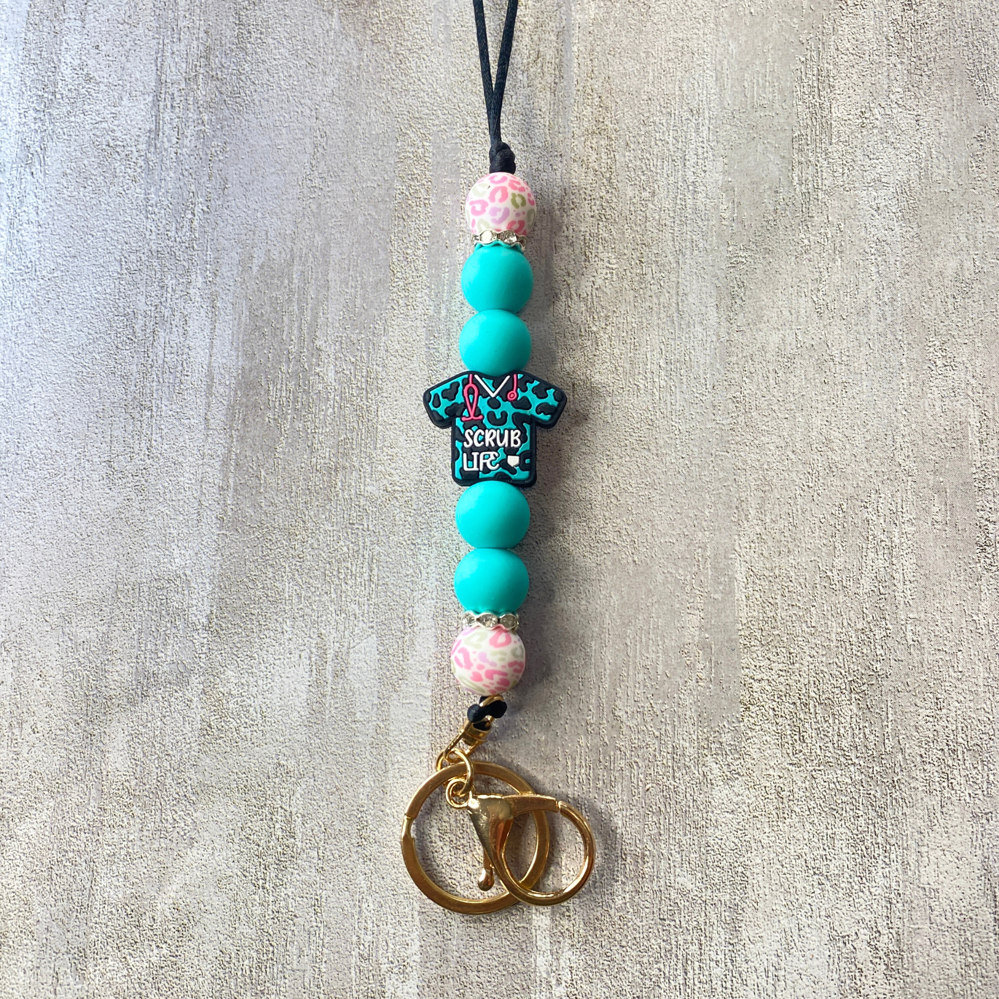 Beaded phone charm with decorative elements on a textured surface