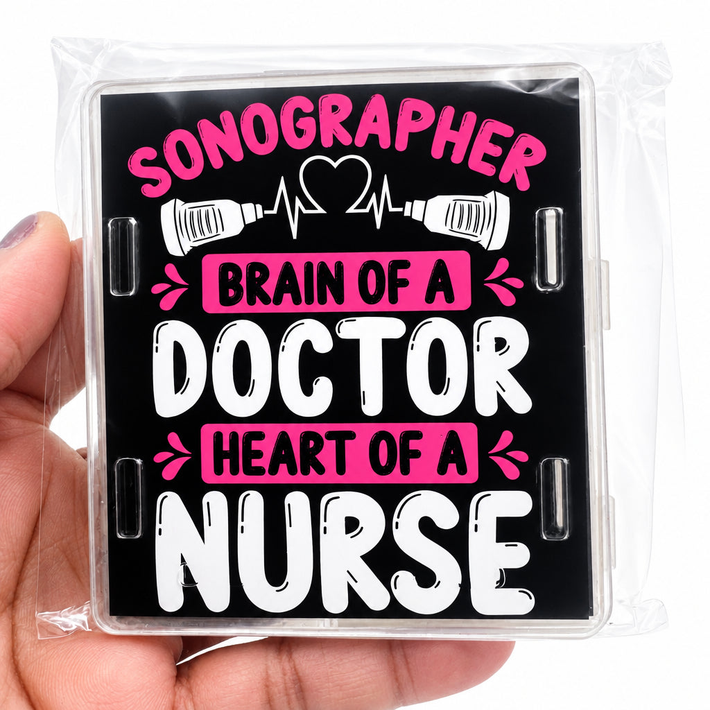 A hand holding a clear plastic-wrapped square sign with the text 'SONOGRAPHER BRAIN OF A DOCTOR HEART OF A NURSE' in pink and white lettering on a black background.