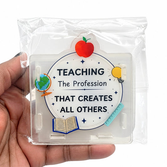 A hand holding a clear plastic case containing a circular sticker that reads 'TEACHING The Profession THAT CREATES ALL OTHERS' with school-themed illustrations including an apple, globe, book, and lightbulb.